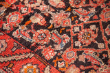 Geometric Herati pattern with red, orange, and beige motifs on charcoal Hamadan runner field.