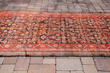 Vintage 1920 Hamadan runner displaying charcoal field, geometric Herati pattern, and red-tangerine border.