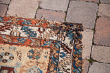 Close-up of antique Karaja runner corner, showing tribal motifs, madder red, and tattered edge.