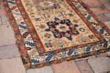 Antique Northwest Persian rug corner with aged patina, geometric blue and rust borders.