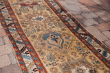 Gold field of the antique Persian runner detailed with geometric teal, red, and brown motifs.