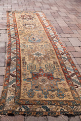 Aged fringe, bold geometric patterns in teal, red, and gold on an antique Karaja runner.