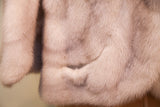Close-up of soft, ivory striped mink fur texture, featuring a subtle pocket.