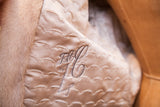 Close-up of vintage ivory fur coat's scalloped quilted lining with embroidered initials.