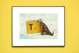 T is for T-Rex photograph showing a miniature dinosaur with a vintage alphabet book on a map.