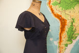 Betsey Johnson black dress featuring V-neck, flutter sleeves, and front button details.