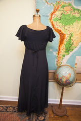 Black Betsey Johnson dress featuring a waist tie and central button closure.