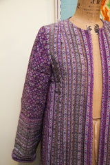 Close-up of purple Andre Laug robe sleeve with dense floral pattern and striped body.