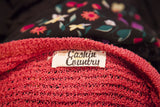 Close-up of the vintage Cashin Country label on a textured raspberry pink knit sweater.