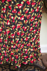 Betsey Johnson dress fabric showcasing vibrant red cherries and light green leaves on black.