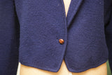 Textured navy blue wool sweater jacket front with single brown wooden button.