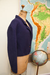 Vintage navy blue slouchy wool sweater jacket with a single wooden button, side view.