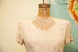Light beige 1940s rayon blouse with sheer embroidered leaf pattern neckline.
