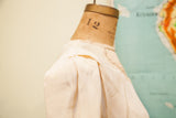 Vintage 40s rayon blouse shoulder with delicate neckline and subtle fabric stains.