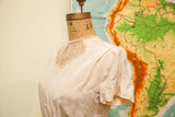 Side view of vintage rayon blouse, ivory fabric with short sleeve and light stains.