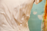 Close-up of light stains on vintage 40s beige rayon blouse fabric.