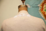 Intricate white beaded floral motif on the soft ivory cashmere sweater back.