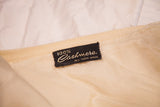 Black and gold '100% Cashmere ALL HAND MADE' tag on an ivory vintage sweater.