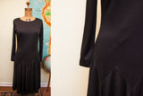 Edith Flagg black dress features V-shaped seam and flowing pleated skirt.