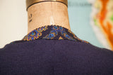 Detail of vintage navy blue sweater neckline with colorful paisley trim.