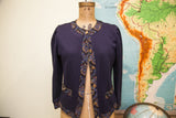 Vintage navy blue sweater, left side with puffed sleeve and intricate patterned hem.