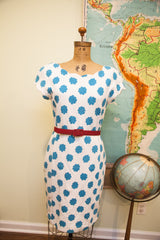 Scalloped neckline and teal floral polka dot print on white vintage dress with red belt.