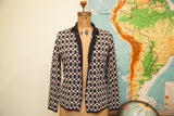 Luminescent buttons and checkerboard pattern on the front of a vintage knit cardigan.