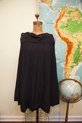 Vintage 60s black romper dress with pleated body, draped neckline, and shoulder bow.