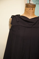Black vintage 60s romper dress with a tied shoulder bow and pleated bodice.