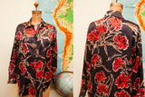 Vintage Moschino blouse: full front view of red flowers and Moschino script on black.