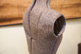 Close-up of the dress form's speckled grey fabric, showing adjustable seams and armhole.