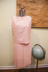 Vintage pink dress top with scattered pearl embellishments and a pleated skirt.