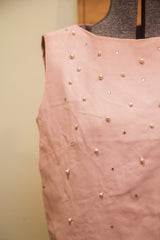 Close-up of vintage pink Patty Woodard dress fabric with scattered pearls and rhinestones.
