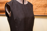 Tailored bust darts and textured silk fabric on the bodice of a vintage black dress.