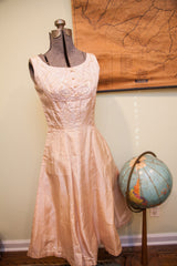 Flowing skirt of a vintage pink taffeta dress, beside a blue globe.
