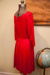 Back view of vintage red dress, detailing the full zipper and pleated low waistline.