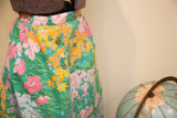 Vibrant floral print, pink waistband, and green side buttons on a vintage Herman Geist skirt.
