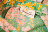 Herman Geist brand label on vibrant floral skirt fabric: pink, yellow, green.