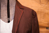 Alberta Feretti jacket lapel with brown pinstripes and bright red stitching.