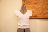 Vintage white knit crop top with V-neck, winged sleeves, and subtle pattern.
