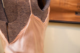 Shimmering satin pink fabric of the vintage gown's delicate neckline and strap.