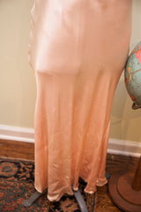 Vintage 1930s pink satin gown fabric, highlighting luxurious drape and subtle age marks.