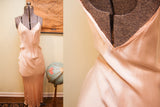 Silky sheen and elegant drape of the vintage pink satin gown's deep back.