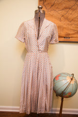 Vintage 1930s rayon day dress, muted pinkish ivory with blue and brown geometric pattern.
