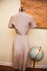 Back view of vintage rayon day dress with pinkish ivory, blue, and red pattern.