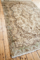 Ivory Vintage Kerman rug corner with low pile, ornate baroque motifs, seafoam green border, fringe.