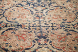 Hand-knotted traditional rug with ornate curvilinear floral patterns in muted navy, beige, rust.