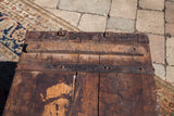 Aged hardwood planks with rusted, riveted metal straps on the antique wooden trunk.