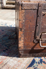 Dovetail joinery and rustic metal strapping on the corner of an antique wooden trunk.