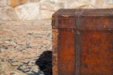 Dovetail joinery and rich orange-red patina on the corner of an antique wooden trunk.
